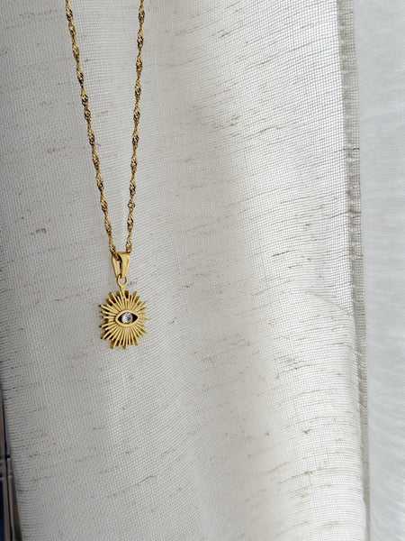 Gold necklace with a sun-shaped eye pendant
