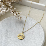 Gold necklace with a circular sunburst pendant
